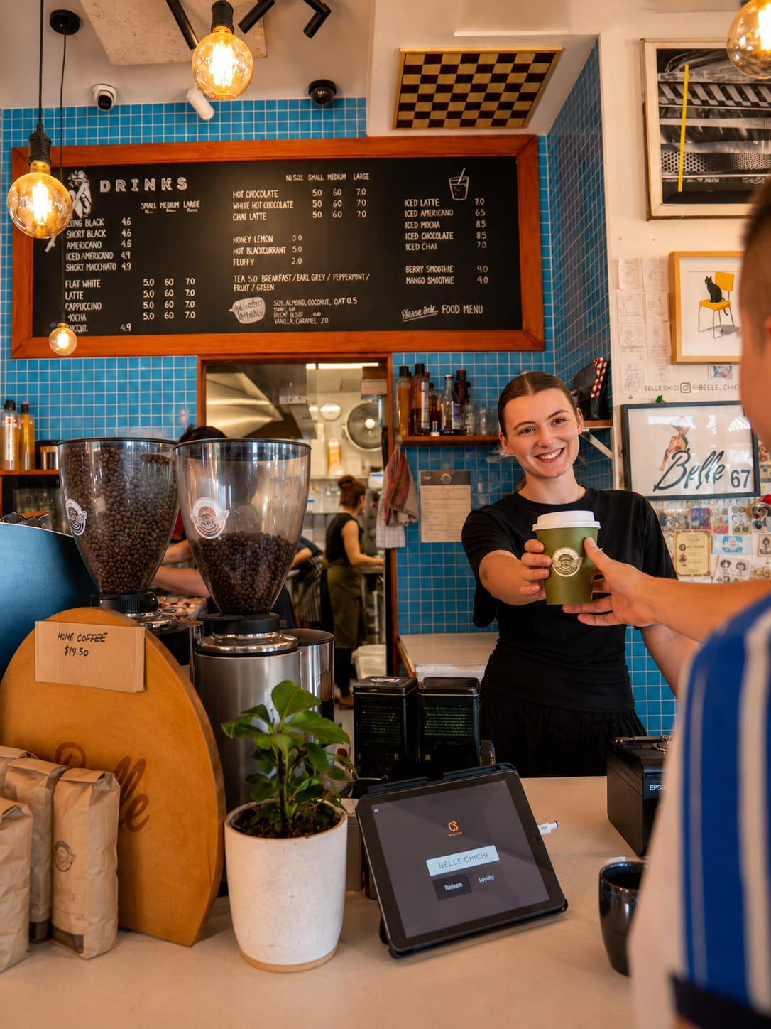A Belle team member handing a takeaway coffee across the counter